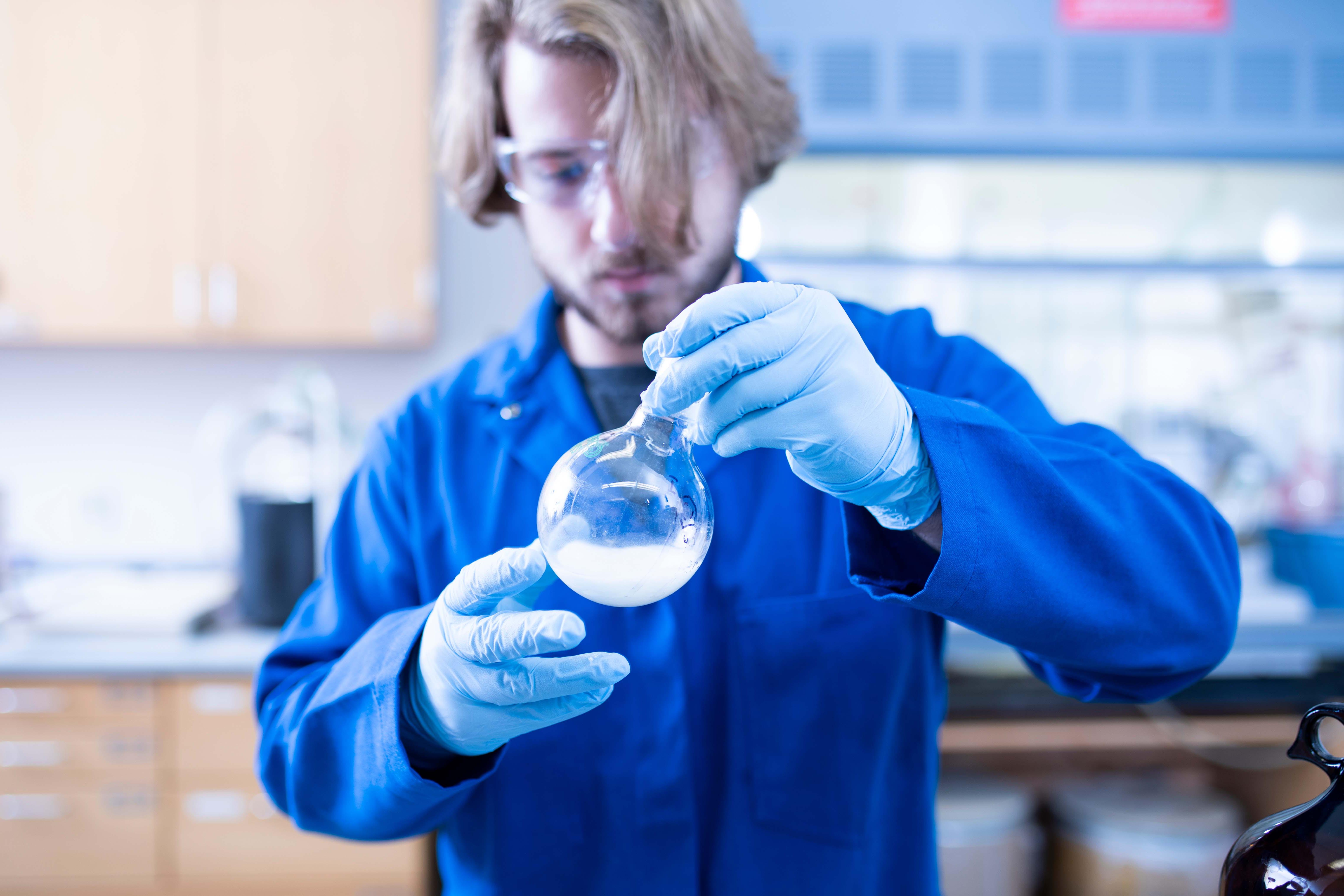 Student holding chemistry equipment up to look at it